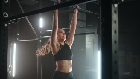 woman-is-doing-pull-up-on-sport-bar-in-gymnastics-hall-training-her-endurance-and-strength